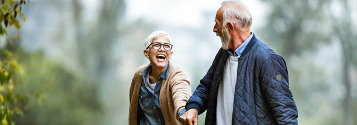 Active senior couple walking and smiling outside.
